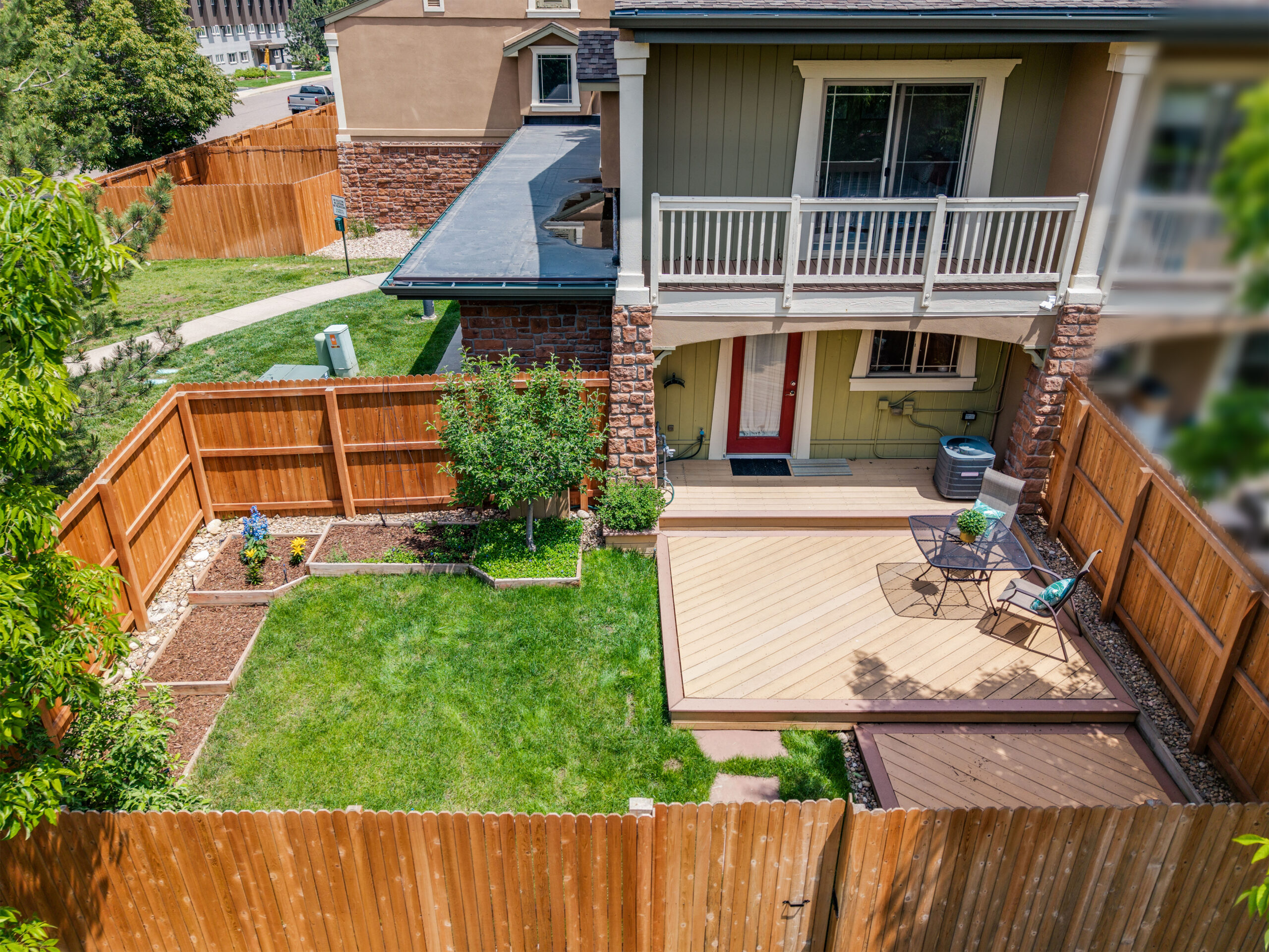Fenced backyard with deck, seating area, and garden beds at 4800 Osage Dr Unit 12B