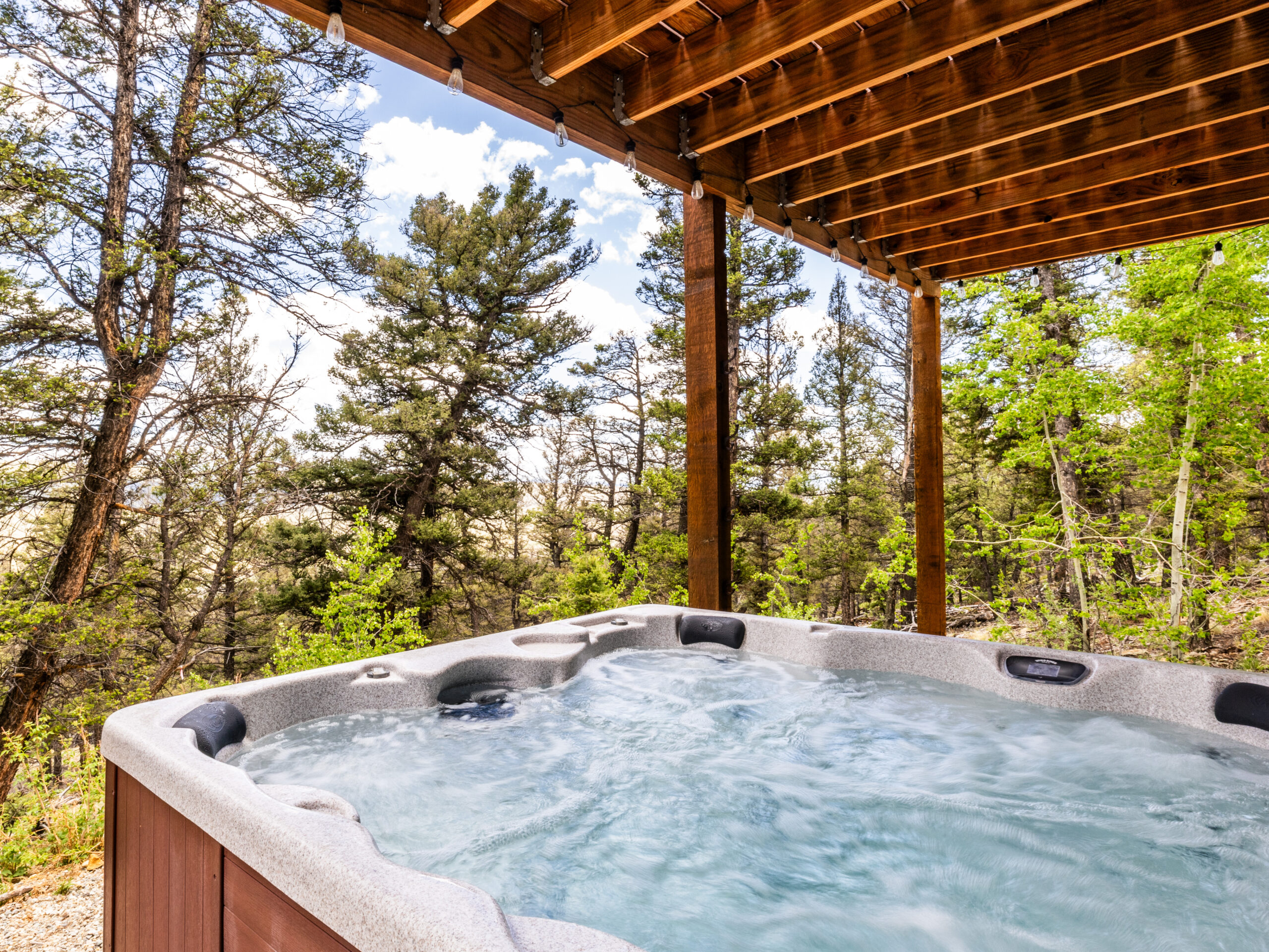 Wind River Spas hot tub on a private deck with trees and mountains in the background.